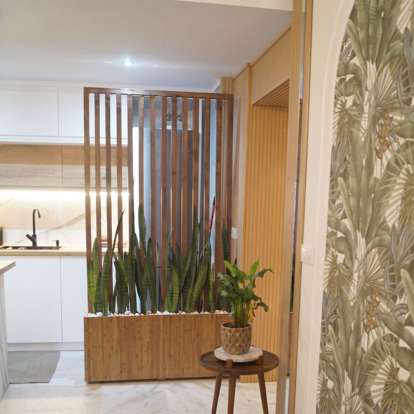 Apartamento San Roque: wooden slatted screen with a snake plant planter separating the kitchen, beside the tropical wallpaper