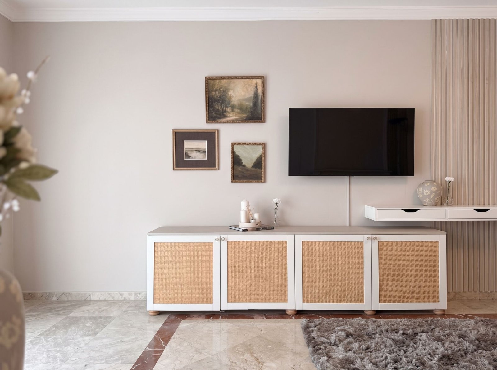 Apartamento San Roque: living room with a low cane-front cabinet, a TV and a group of landscape paintings