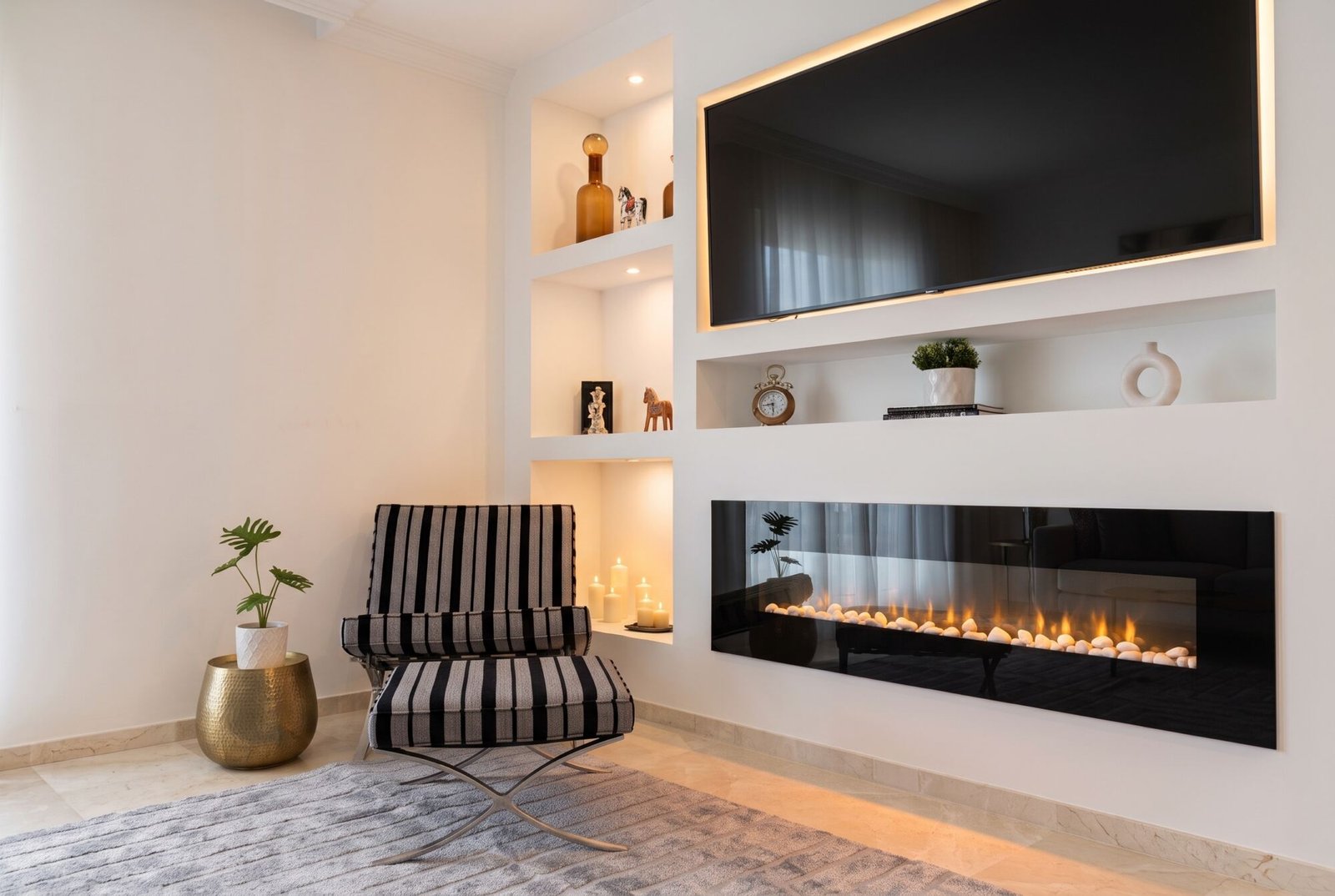 San Roque Club: built-in unit with lit niches, an electric fireplace and a striped armchair